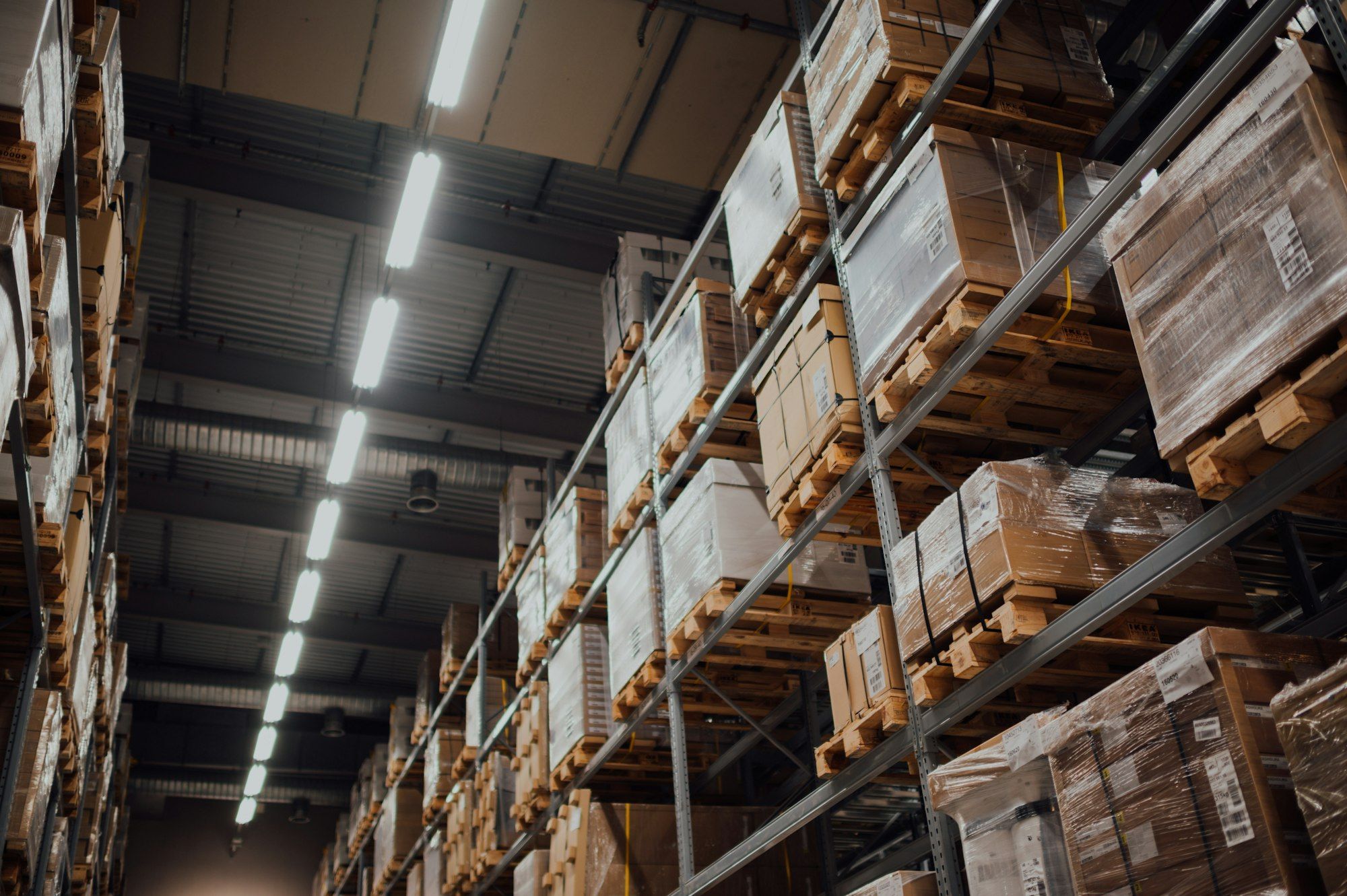 Boxed stock on pallets along warehouse shelving.