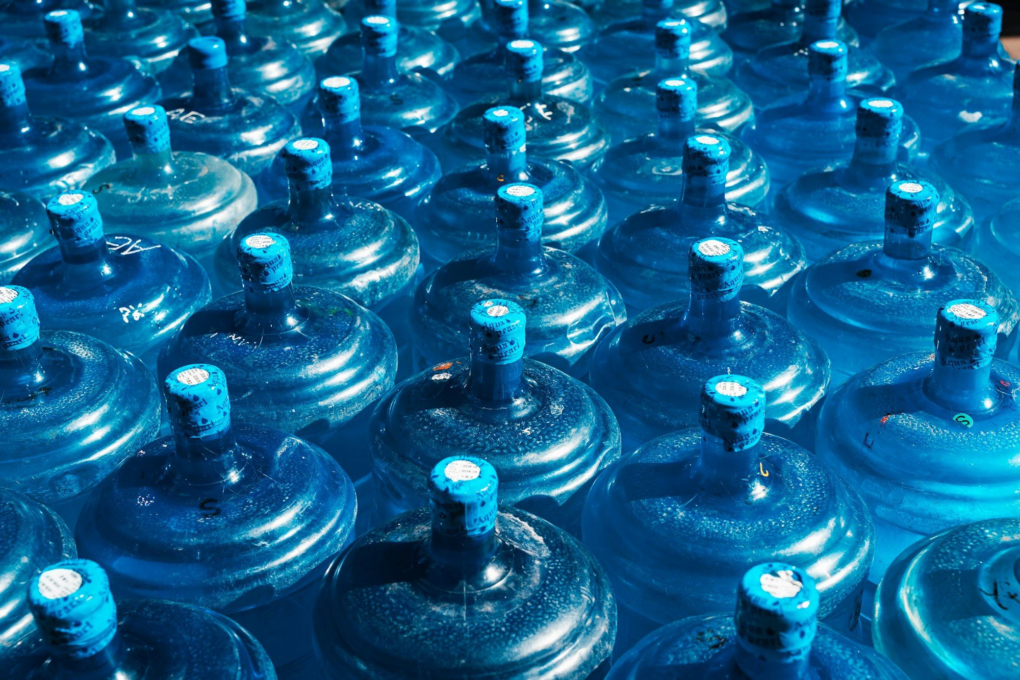 Rows of large blue refill bottles for water dispensers.