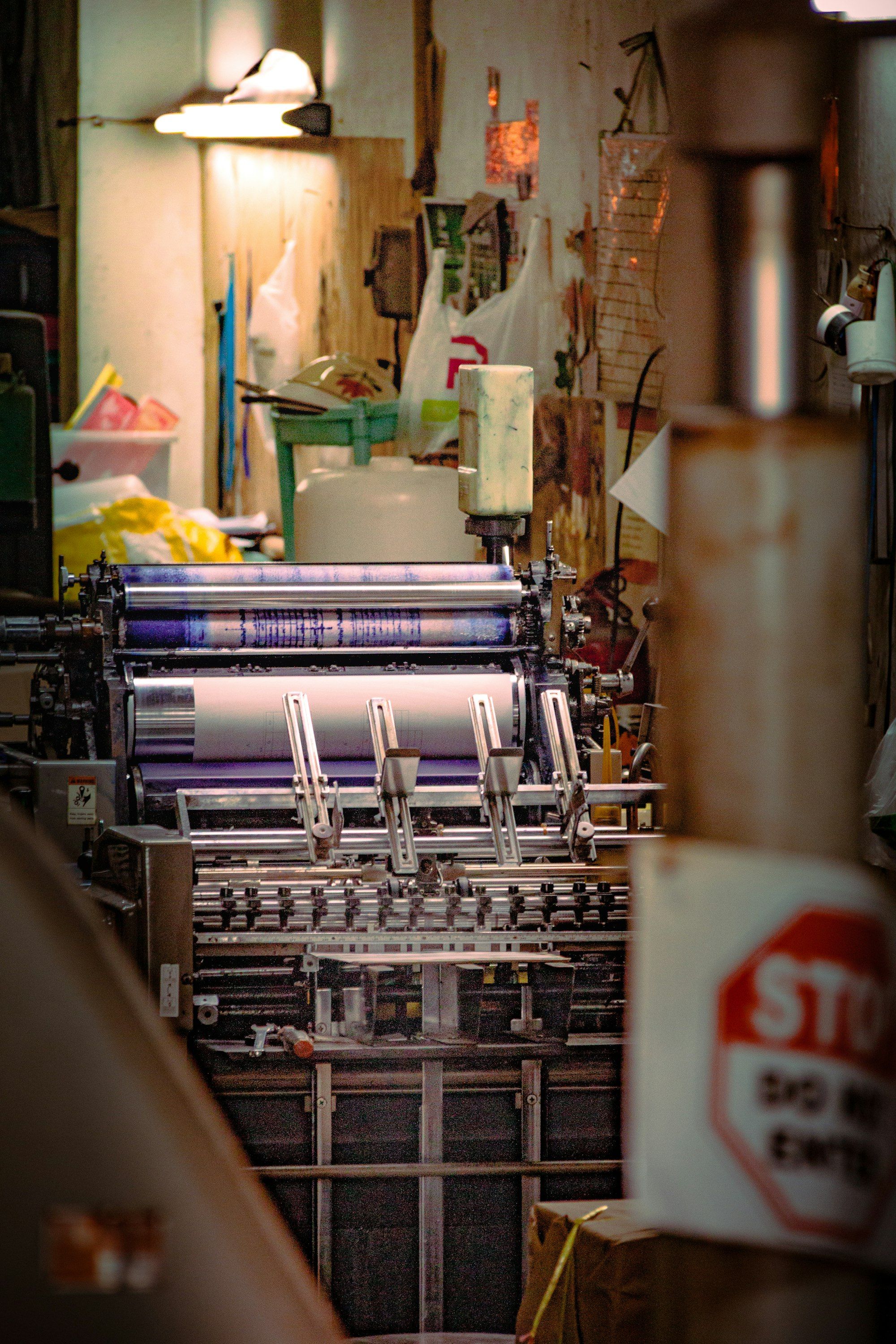An offset printing press with ink rollers in a print shop.